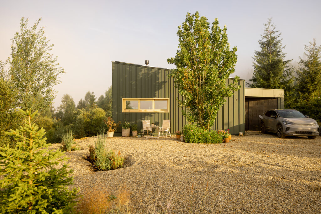 A modern cabin nestled in nature, featuring a sleek design and an electric vehicle parked in the driveway. Perfect for eco-friendly getaways and enjoying a peaceful retreat in the mountains