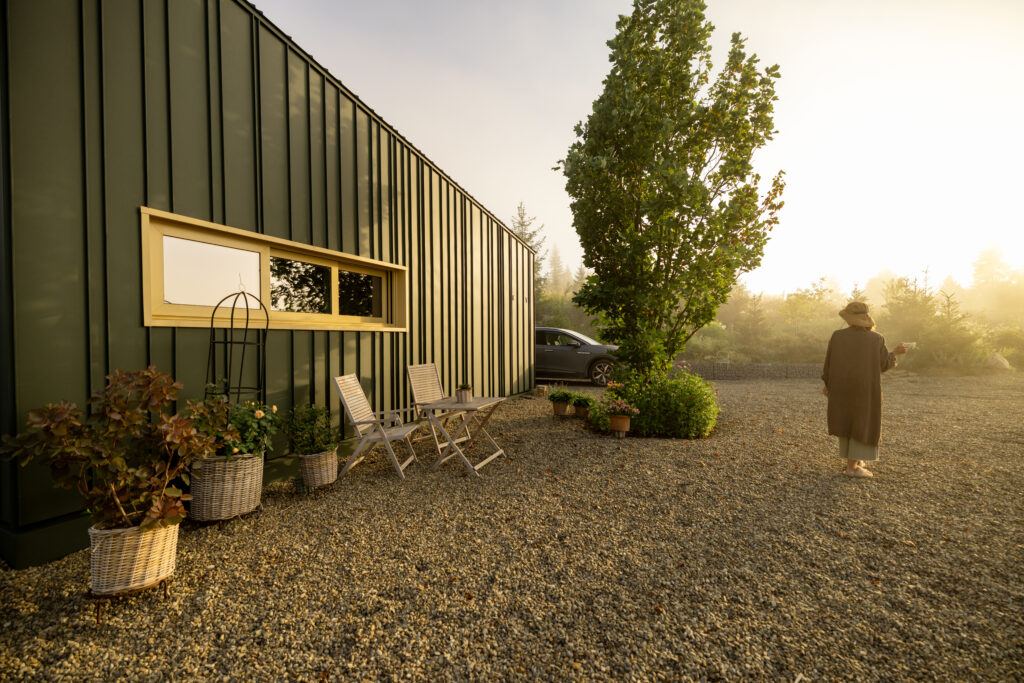 A person enjoys the peaceful morning light outside a modern cabin, capturing the essence of tranquility and solitude in nature